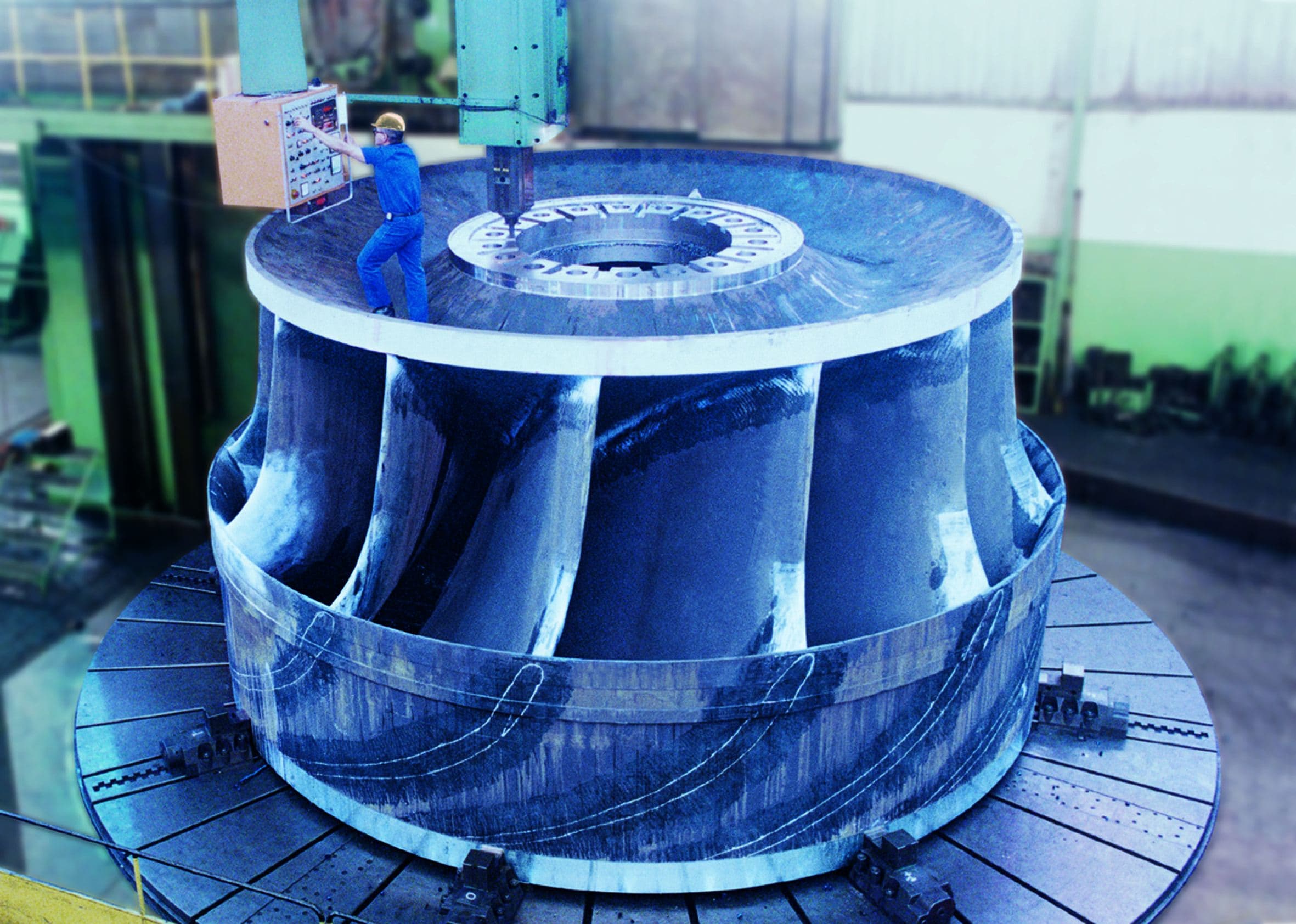 A Francis runner on a vertical carousel lathe — the finishing cut that fixes the machine's hydraulic profile.